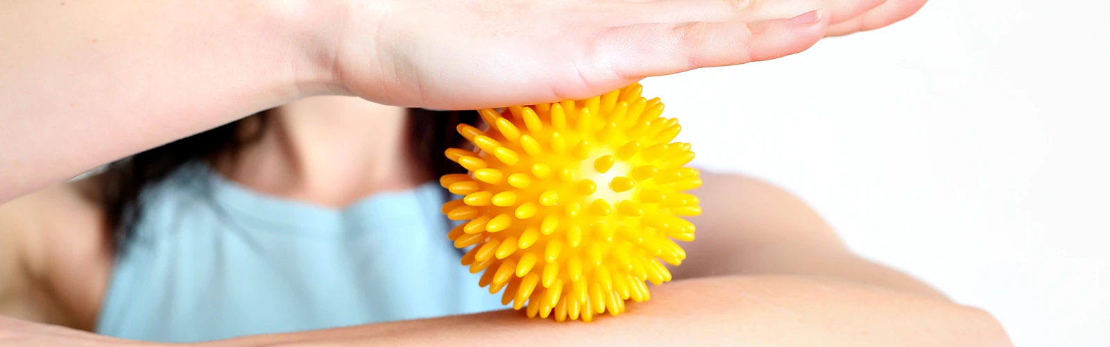 Frau massiert Arm mit Igelball Frau massiert Arm mit Igelball